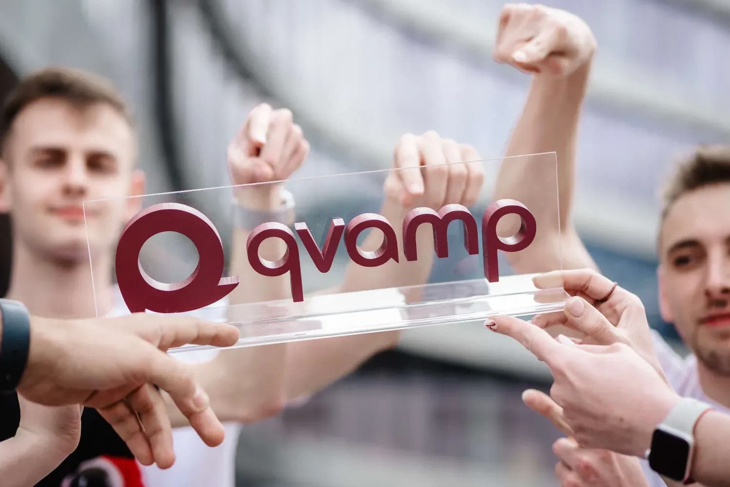 Ruce týmu Qvampu drží logo Qvamp